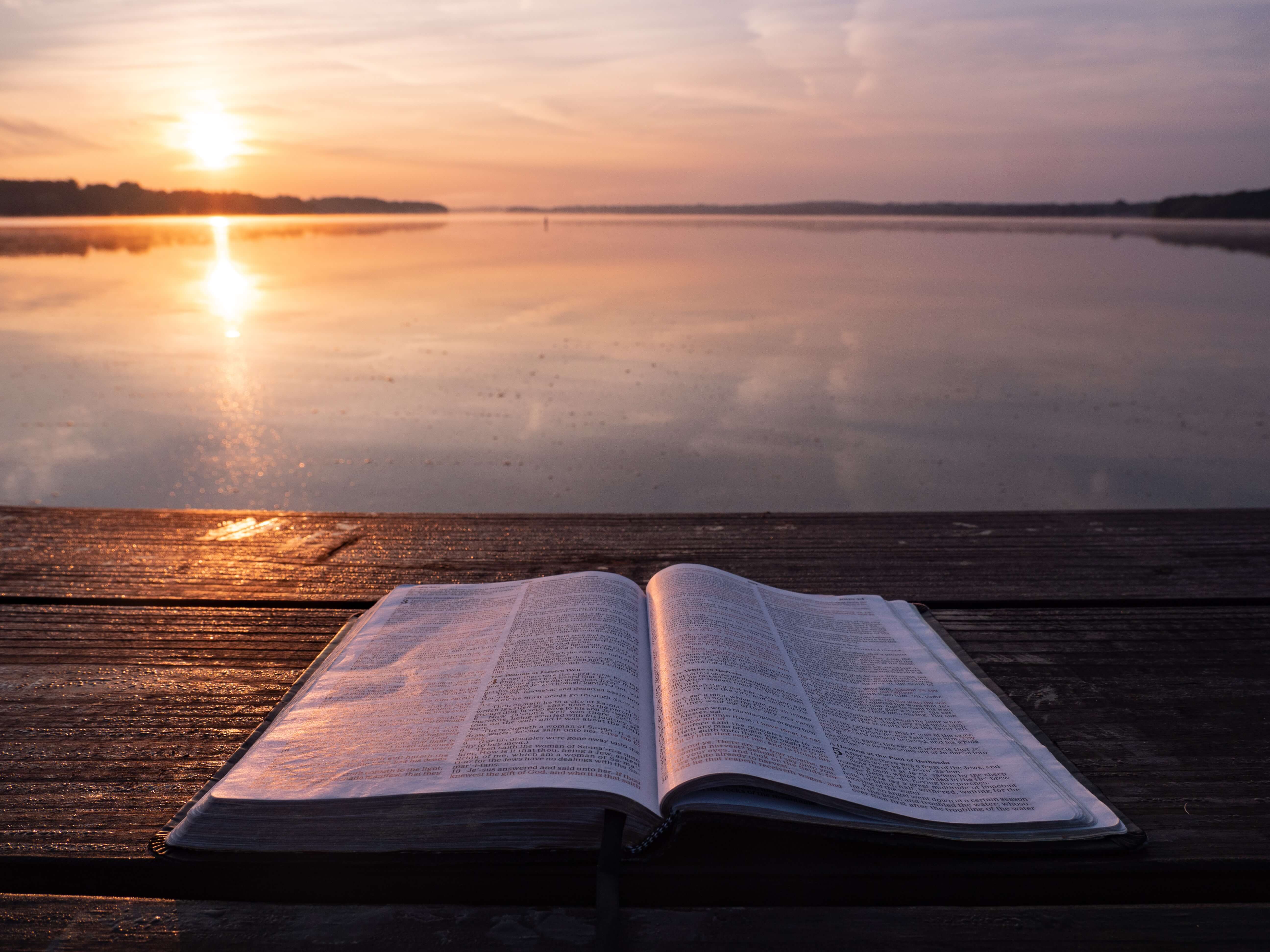 open bible in front of a lake